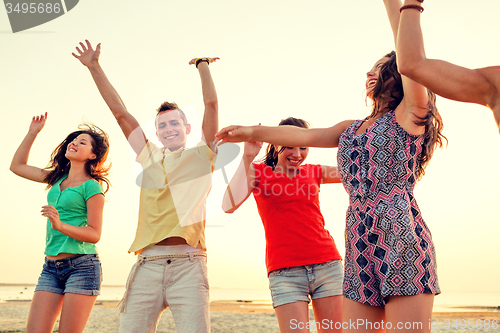 Image of smiling friends dancing on summer beach