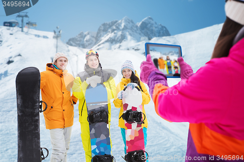 Image of happy friends with snowboards and tablet pc