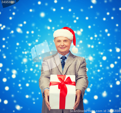 Image of smiling man in suit and santa helper hat with gift