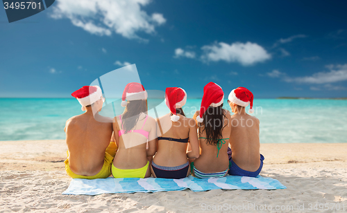 Image of group of friends in santa helper hats on beach