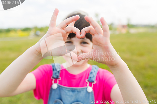 Image of happy little girl making heart shape gesture