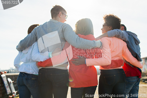 Image of group of happy teenage friends hugging on street