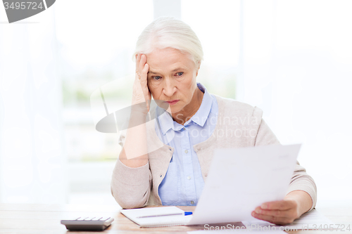 Image of senior woman with papers and calculator at home