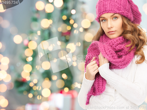 Image of woman in hat and scarf over christmas tree lights