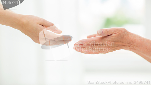 Image of close up of senior and young woman hands