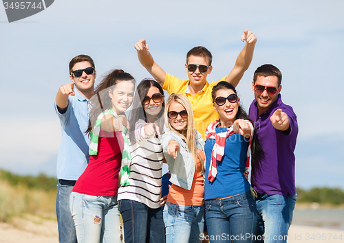 Image of group of happy friends hugging on beach