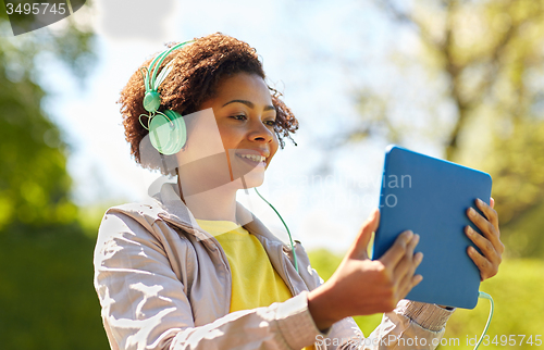 Image of happy african woman with tablet pc and headphones