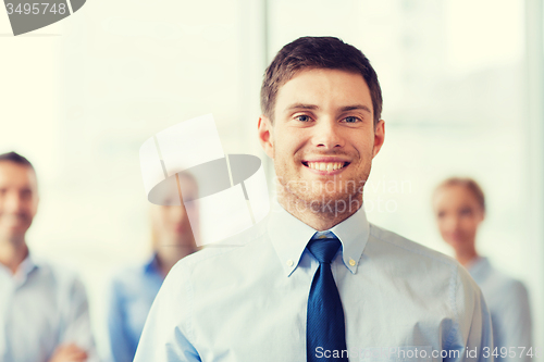 Image of smiling businessman with colleagues in office