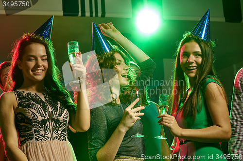 Image of smiling friends with glasses of champagne in club