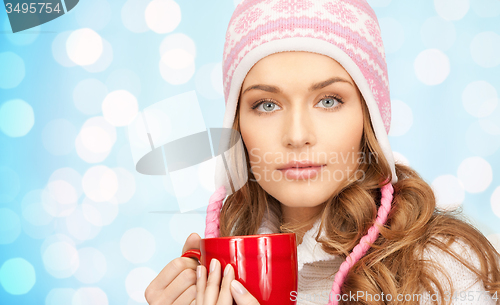 Image of happy young woman in winter hat with cup