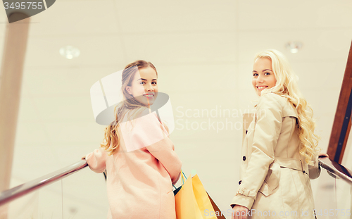 Image of happy young women with shopping bags in mall