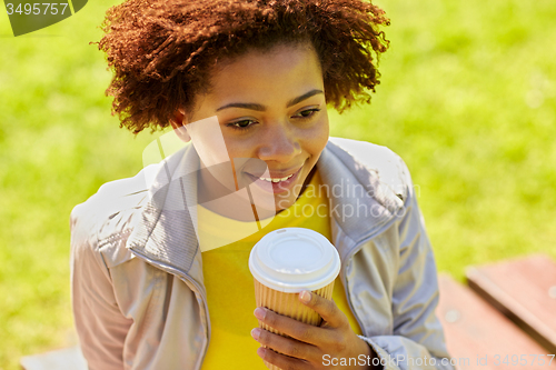 Image of smiling african woman drinking coffee outdoors 