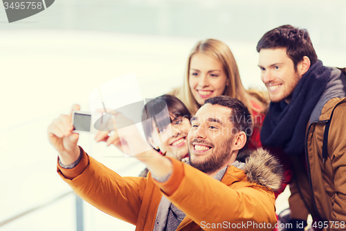 Image of happy friends with camera on skating rink
