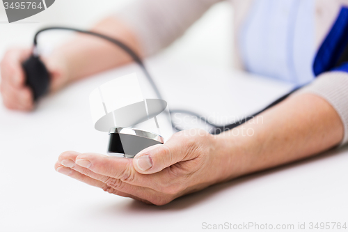 Image of old woman with tonometer checking blood pressure