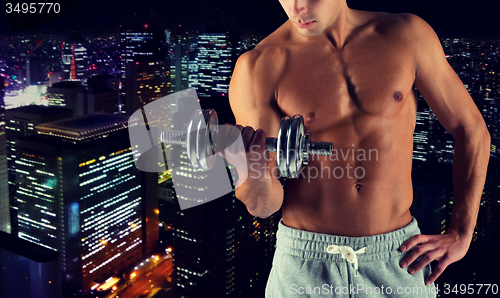 Image of close up of young man with dumbbell flexing biceps