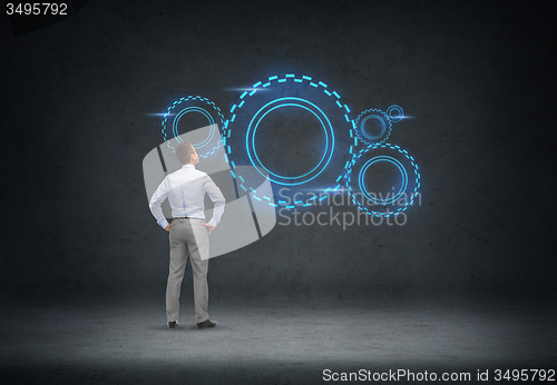 Image of businessman looking at cogwheel projection