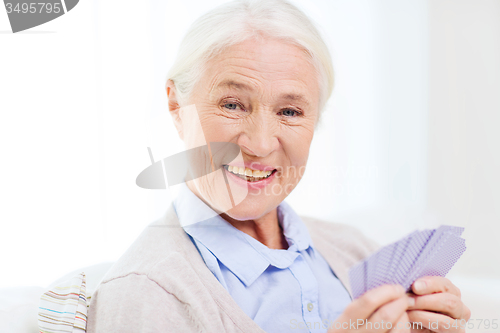 Image of happy senior woman playing cards at home