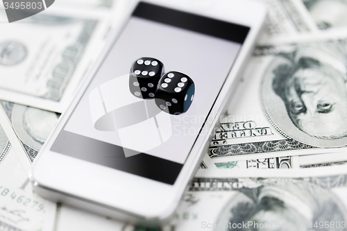 Image of close up of dice with smart phone and cash money