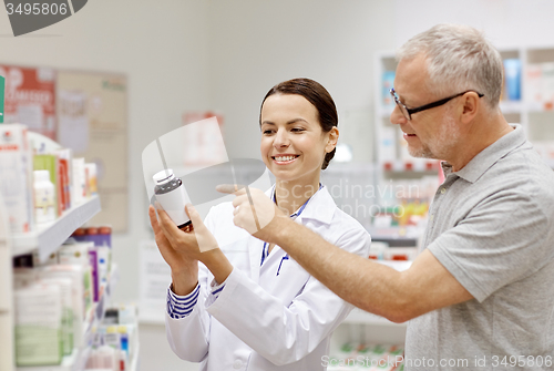 Image of pharmacist showing drug to senior man at pharmacy