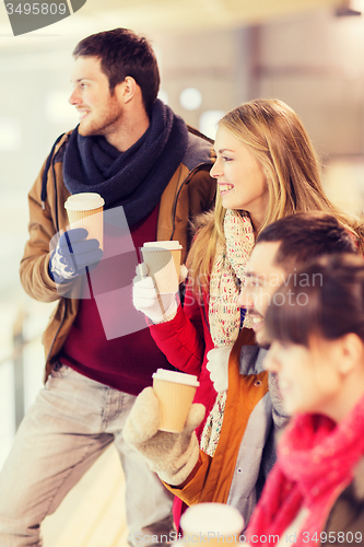 Image of happy friends with coffee cups on skating rink