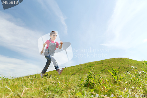 Image of happy little girl running on green summer field