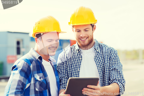 Image of smiling builders in hardhats with tablet pc