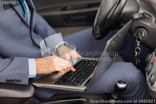 Image of close up of young man with laptop driving car