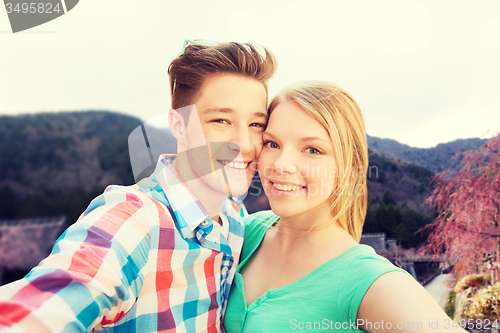 Image of smiling couple taking selfie over asian landscape