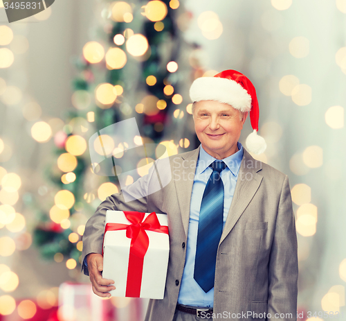 Image of smiling man in suit and santa helper hat with gift