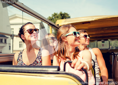 Image of group of smiling friends traveling by tour bus