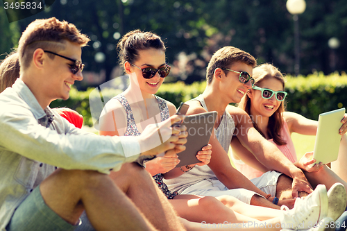 Image of smiling friends with tablet pc computers in park