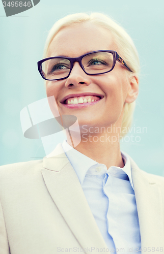 Image of young smiling businesswoman over office building
