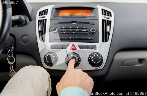 Image of close up of male hand using climate control in car