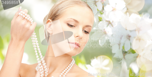 Image of woman with pearl necklace over cherry blossom