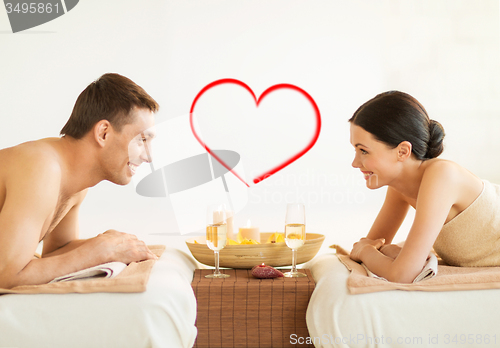 Image of smiling couple with candles and drinks in spa