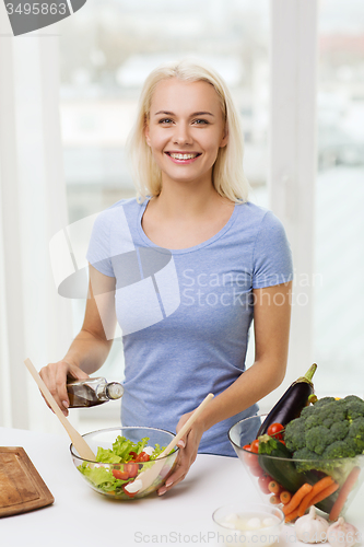 Image of smiling woman cooking vegetable salad at home