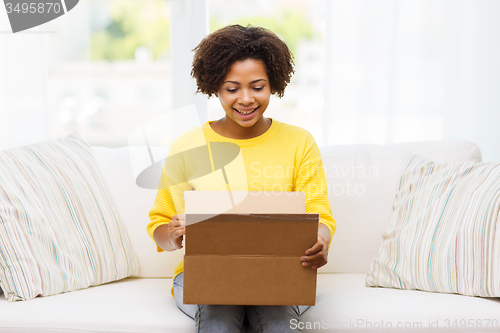 Image of happy african young woman with parcel box at home