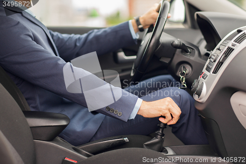 Image of close up of young man in suit driving car