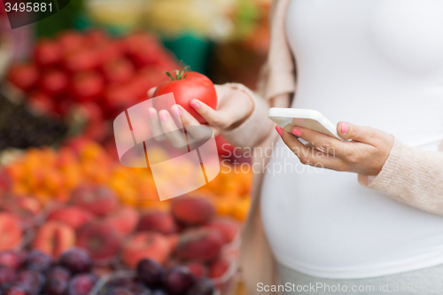 Image of pregnant woman with smartphone at street market