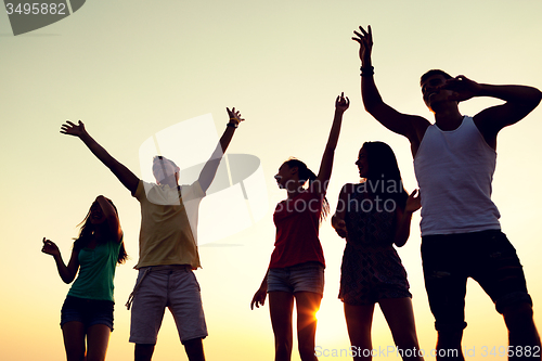 Image of smiling friends dancing on summer beach