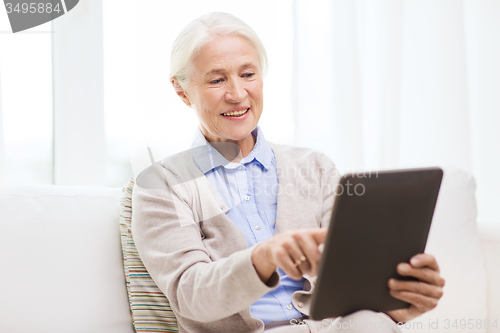 Image of happy senior woman with tablet pc at home