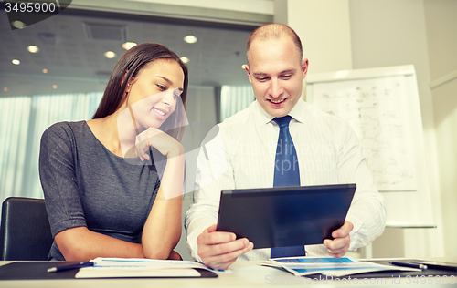 Image of smiling businesspeople with tablet pc in office