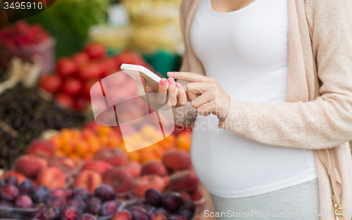 Image of pregnant woman with smartphone at street market