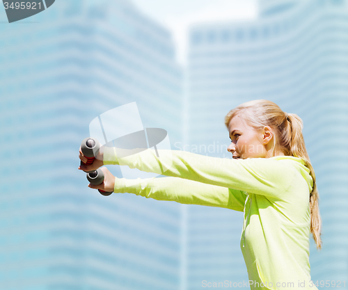 Image of sporty woman with light dumbbells outdoors