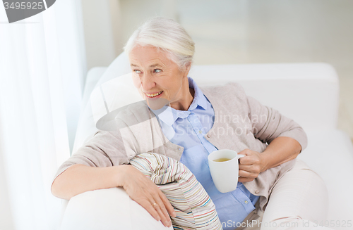 Image of happy senior woman with cup of tea at home