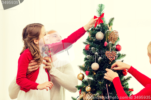 Image of smiling family decorating christmas tree at home