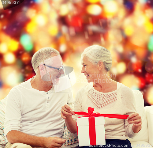 Image of happy senior couple with gift box at home