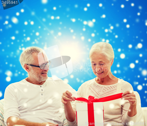Image of happy senior couple with gift box at home
