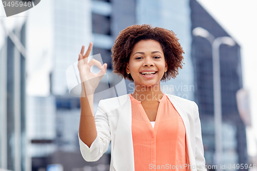 Image of happy african businesswoman showing ok in city