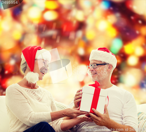 Image of happy senior couple with gift box at home